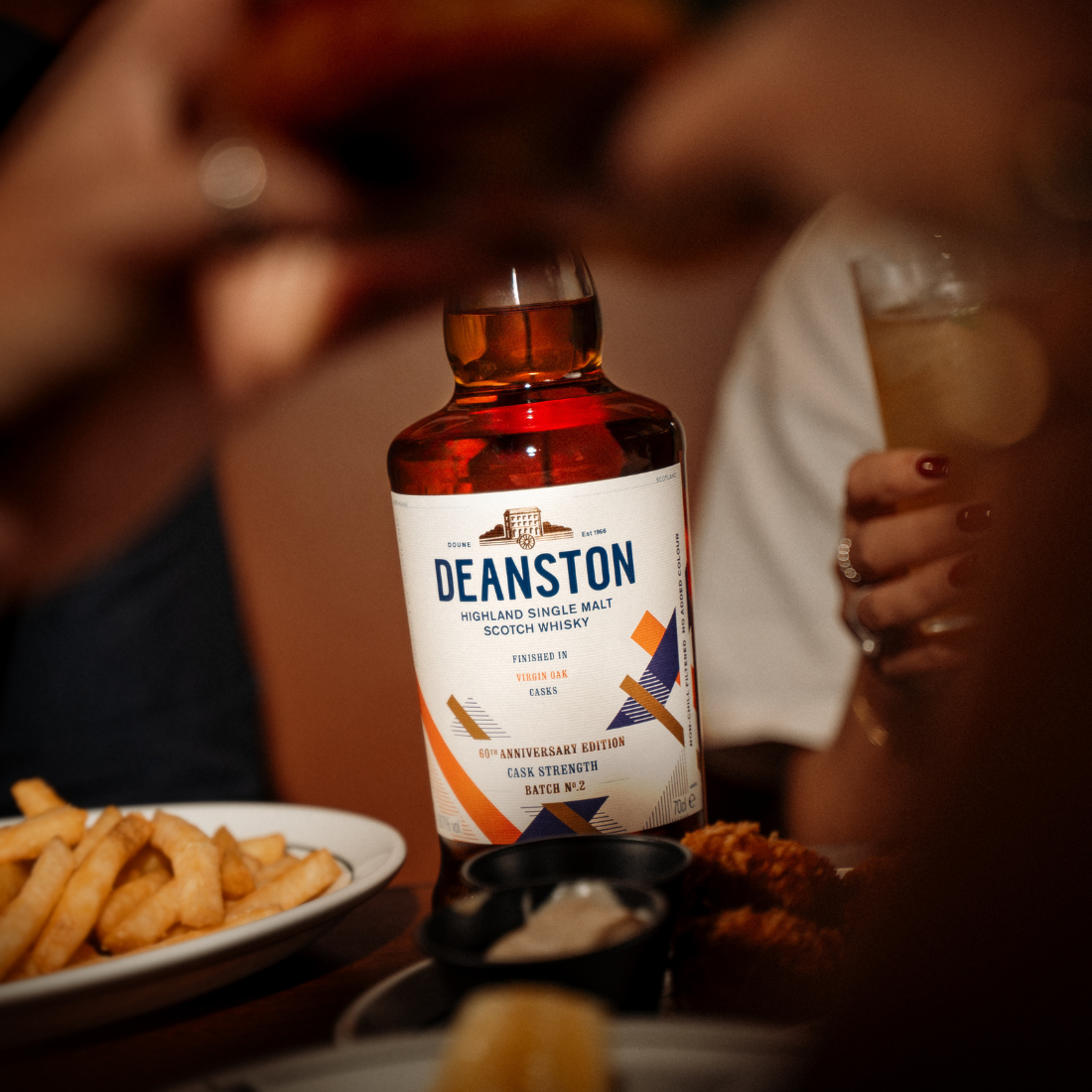 A bottle of Virgin Oak Cask Strength: 2026 Edition is sitting amongst a table of food.